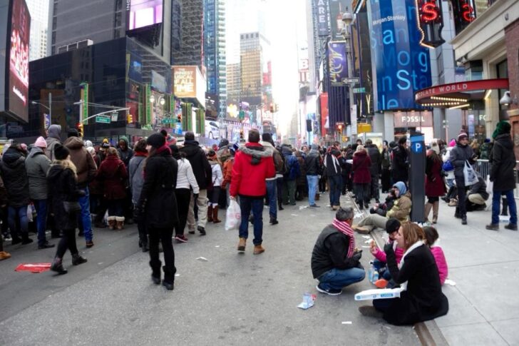 座り込んでピザを食べながら待つ人も